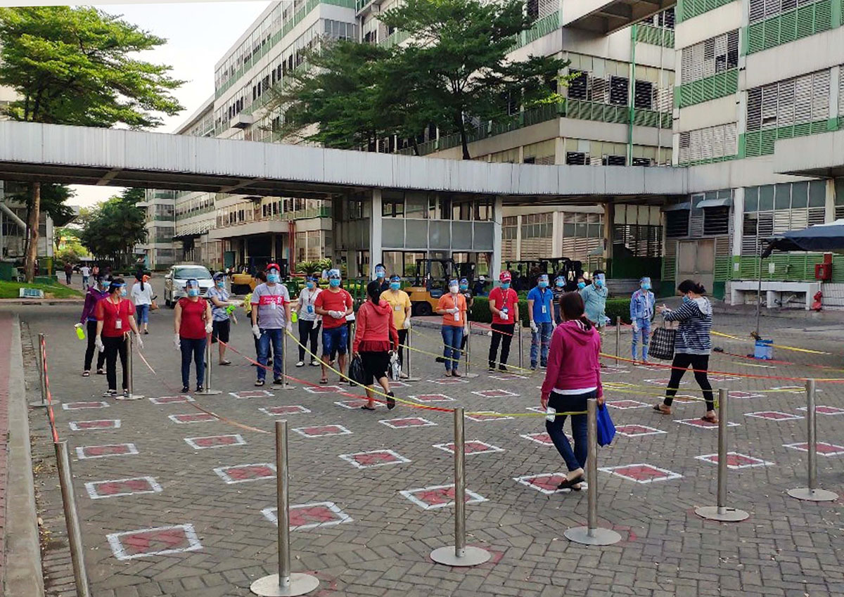 Công nhân Công ty TNHH Pouyuen Việt Nam thực hiện giãn ca, rửa tay khử trùng và đo thân nhiệt trước khi vào xưởng.