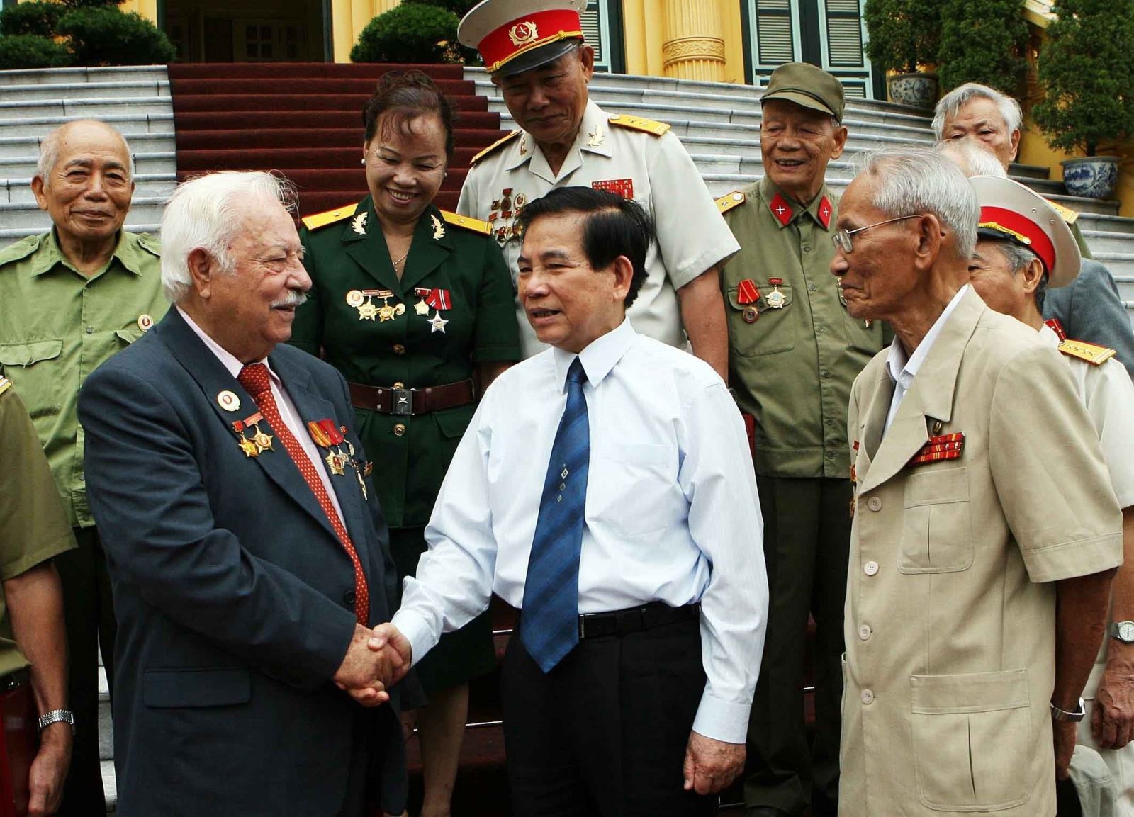Chủ tịch nước Nguyễn Minh Triết (áo trắng) thăm hỏi cựu chiến binh Kostas Sarantidis Nguyễn Văn Lập, Đảng viên Đảng Cộng sản Việt Nam, nguyên chiến sĩ Trung đoàn 803, Liên khu 5 (ngày 30/6/2010, tại Phủ Chủ tịch). Ảnh: Nguyễn Khang - TTXVN